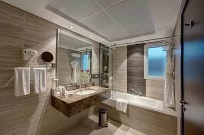 a bathroom with a sink and a tub and a mirror at Omega Hotel Dubai in Dubai