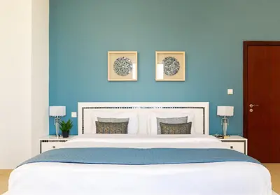 a bedroom with a large white bed with a blue wall at Maison Privee - Premium Apt in the Heart of JBR Beach, Dubai in Dubai