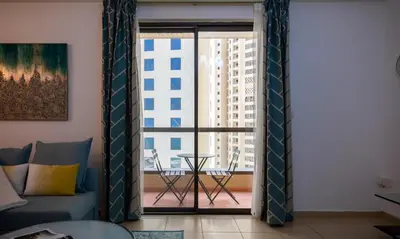 a living room with a couch and a large window at Maison Privee - Premium Apt in the Heart of JBR Beach, Dubai in Dubai