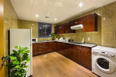 a kitchen with a refrigerator and a washer and dryer at Rolla Residence Hotel Apartment in Dubai