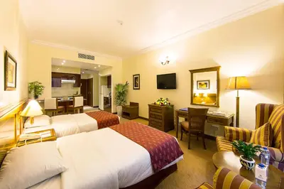a hotel room with two beds and a desk at Rolla Residence Hotel Apartment in Dubai