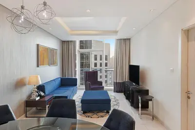 a living room with a blue couch and chairs at DAMAC Maison Distinction in Dubai