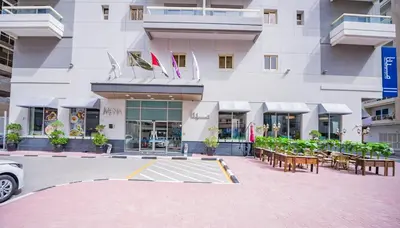 a building with tables and chairs in front of it at MENA Plaza Hotel Albarsha At The Mall in Dubai