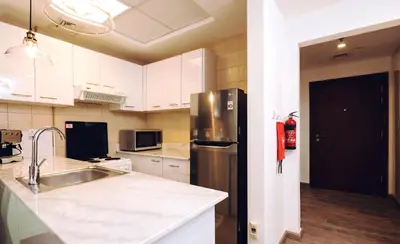 a kitchen with white cabinets and a stainless steel refrigerator at Near Burj Khalifa, DownTown - Burj Al Nujoom in Dubai