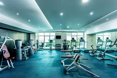 a gym with cardio equipment and people in the background at Park Regis Kris Kin Hotel in Dubai