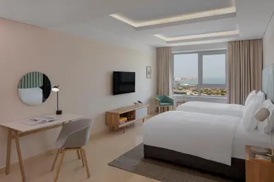 a hotel room with a bed and a desk and a window at Staybridge Suites Dubai Internet City by IHG in Dubai