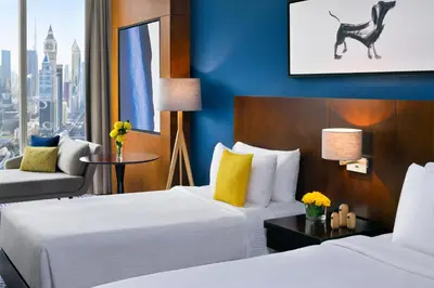 a hotel room with two beds and a chair at voco Dubai by IHG in Dubai