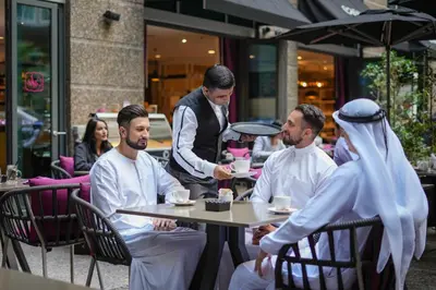 a group of men sitting at a table in a restaurant at Ritz Carlton DIFC Downtown Dubai in Dubai
