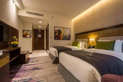a hotel room with two beds and a television at Golden Tulip Media Hotel in Dubai