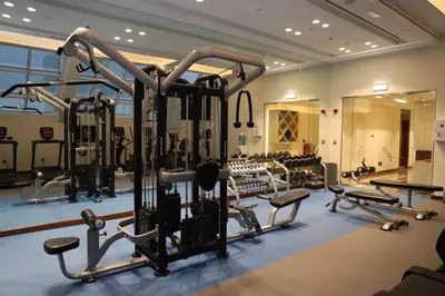 a gym with several treadmills and machines at Golden Tulip Media Hotel in Dubai