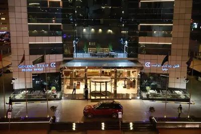 a car parked in front of a building at night at Golden Tulip Media Hotel in Dubai