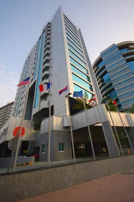 a tall building with flags in front of it at Gulf Oasis Hotel Apartments Fz LLC in Dubai