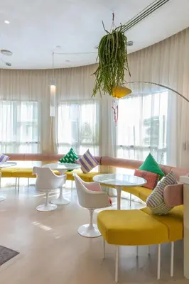 a room with yellow and white chairs and tables at Beach Walk Boutique Jumeirah in Dubai