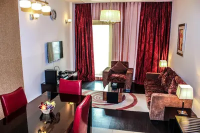 a living room with a table and red curtains at Dunes Hotel Apartment Oud Metha, Bur Dubai in Dubai