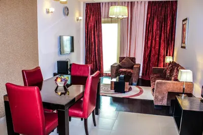 a living room with a table and red chairs at Dunes Hotel Apartment Oud Metha, Bur Dubai in Dubai