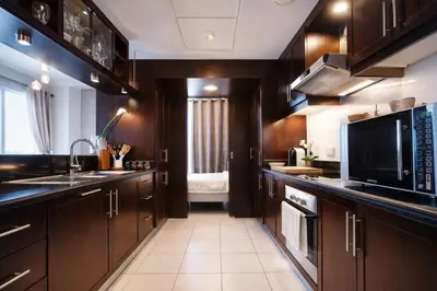 a kitchen with wooden cabinets and a sink and a microwave at Elite Royal Apartment - Full Burj Khalifa & Fountain view - Opal - 2 bedrooms plus 1 open bedroom without partition in Dubai