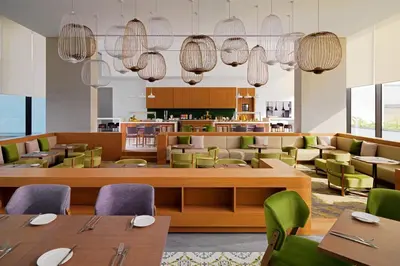 a restaurant with wooden tables and green chairs at Element Me'aisam, Dubai in Dubai