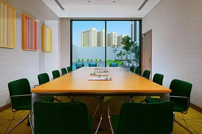 a conference room with a large wooden table and green chairs at Element Me'aisam, Dubai in Dubai