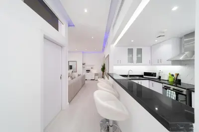 a white kitchen with a black counter and white appliances at Jbr beach walk 2 bedrooms front sea in Dubai
