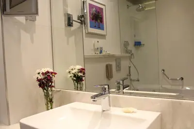 a bathroom with a sink and a mirror and flowers at Gulf Inn Hotel Al Nasr Formerly Roda Links Al Nasr in Dubai