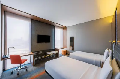 a hotel room with two beds and a desk and a tv at Aloft Me'aisam, Dubai in Dubai