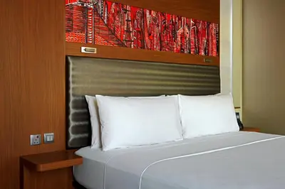 a bed with white pillows in a room at Aloft Me'aisam, Dubai in Dubai