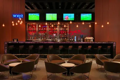 a bar in a room with chairs and wine bottles at Aloft Me'aisam, Dubai in Dubai
