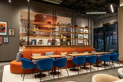 a restaurant with tables and blue chairs at Aloft Me'aisam, Dubai in Dubai