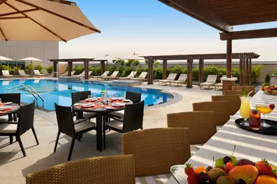 a patio with a table and chairs and a pool at Crowne Plaza - Dubai Jumeirah by IHG in Dubai