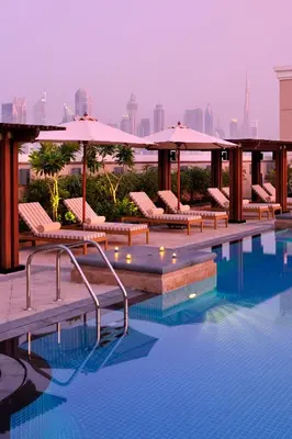 a swimming pool with chairs and umbrellas on a building at Crowne Plaza - Dubai Jumeirah by IHG in Dubai