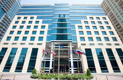 a tall building with flags in front of it at Marina Byblos Hotel in Dubai