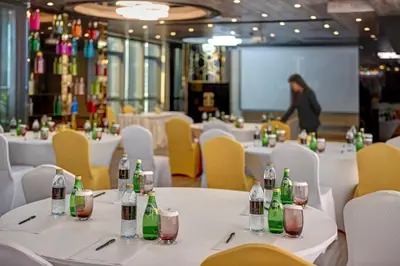 a dining room with white tables and yellow chairs at Gevora Hotel in Dubai