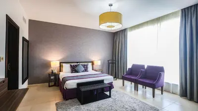 a bedroom with a bed and two purple chairs at Nassima Tower Hotel Apartments in Dubai