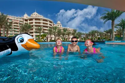 three people in the water at a resort at Kempinski Hotel Palm Jumeirah in Dubai
