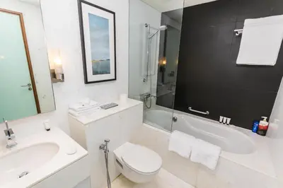 a white bathroom with a toilet and a sink and a tub at Westminster Dubai Mall in Dubai