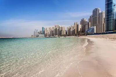 a beach in front of a city with tall buildings at Hilton Dubai The Walk in Dubai