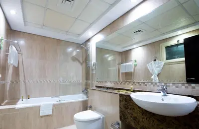 a bathroom with a sink and a toilet and a mirror at First Central Hotel Suites in Dubai