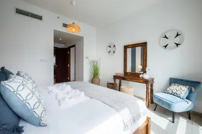 a bedroom with a white bed and a blue chair at Maison Privee - Exclusive Apt with Burj Khalifa Next Door in Dubai