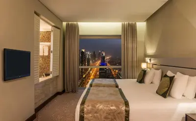 a hotel room with a bed with a view of a city at The Tower Plaza Hotel Dubai in Dubai