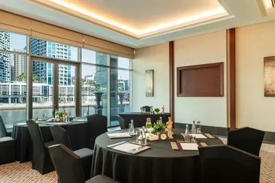 a dining room with tables and chairs and windows at Renaissance Business Bay Hotel, Dubai in Dubai
