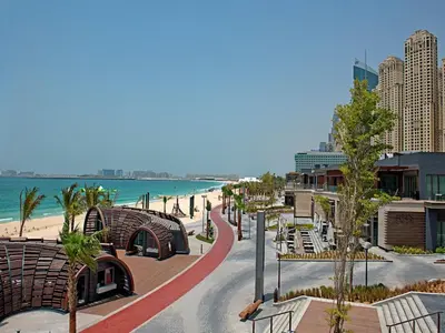 a street with benches and the beach and buildings at 2br Beach front Sea View in Dubai