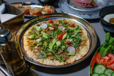 a pizza on a plate on a table at Ritz Carlton Residences DIFC Downtown Dubai in Dubai