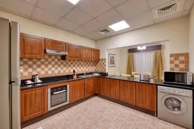 a kitchen with wooden cabinets and a washer and dryer at Pearl Marina Hotel Apartments in Dubai