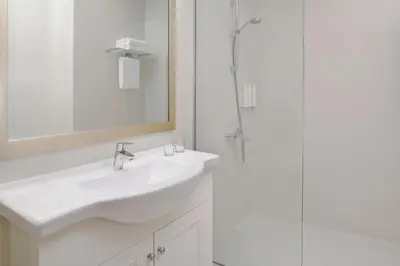 a white bathroom with a sink and a shower at Delta Hotels by Marriott Dubai Investment Park in Dubai