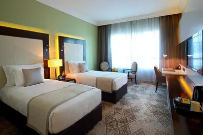 a hotel room with two beds and a desk at Elite Byblos Hotel in Dubai