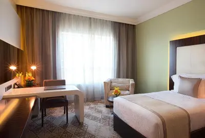 a hotel room with a bed and a desk with a laptop at Elite Byblos Hotel in Dubai