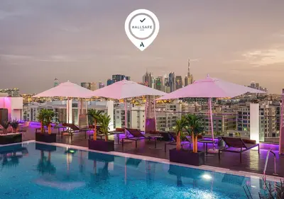 a pool with purple chairs and umbrellas on a building at The Canvas Dubai - MGallery Hotel Collection in Dubai