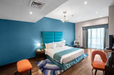a blue room with a bed and two chairs at City Premiere Hotel Apartments - Dubai in Dubai
