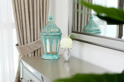 a blue lantern on a table with a flower in a vase at Luxury Casa - Grand Sea View Apartment JBR Beach 2BR in Dubai