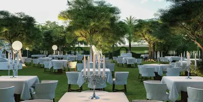 a group of tables and chairs with white tables and trees at Delano Dubai at Bluewaters in Dubai